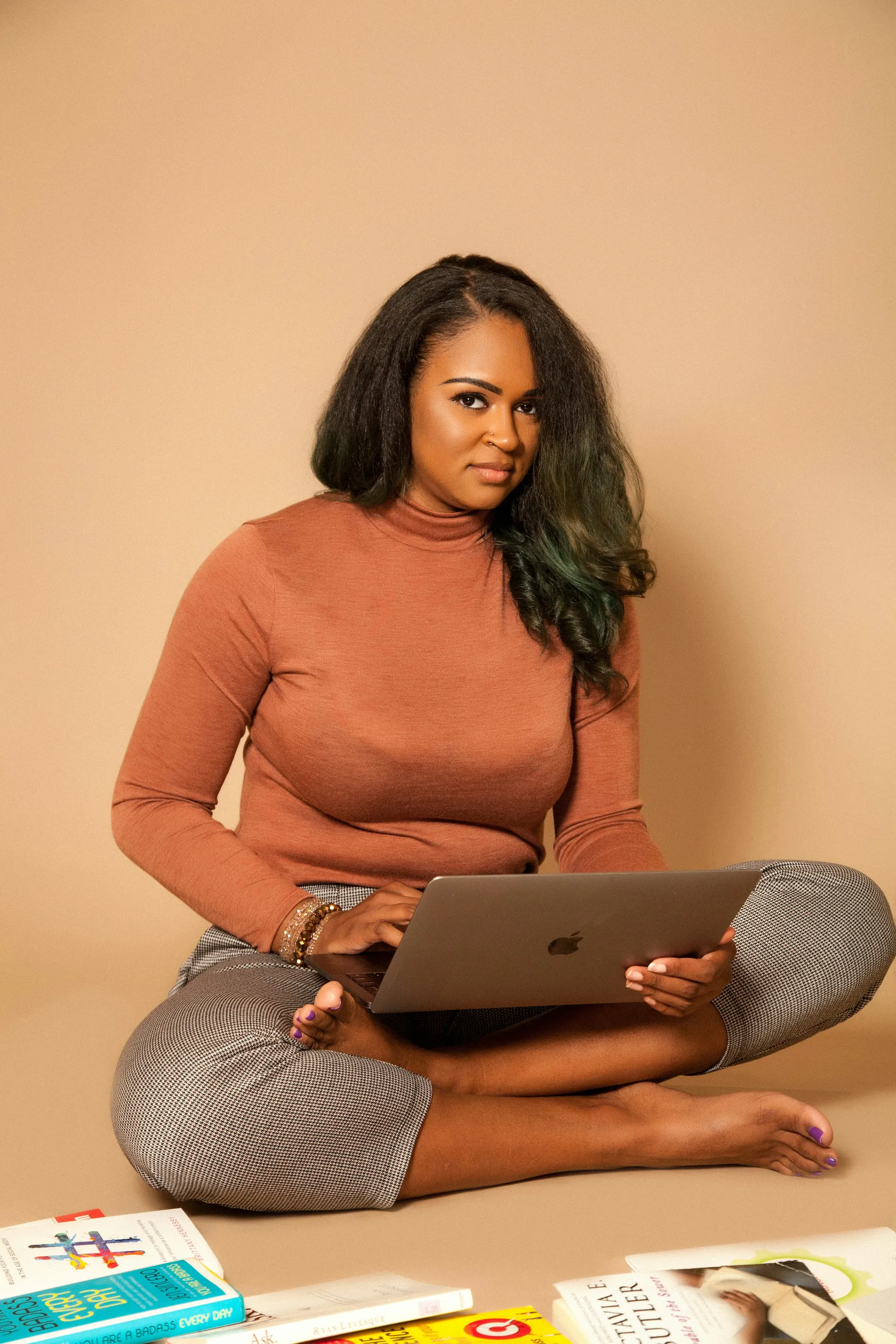 Black woman working with a laptop and books nearby, representing learning and financial agency.